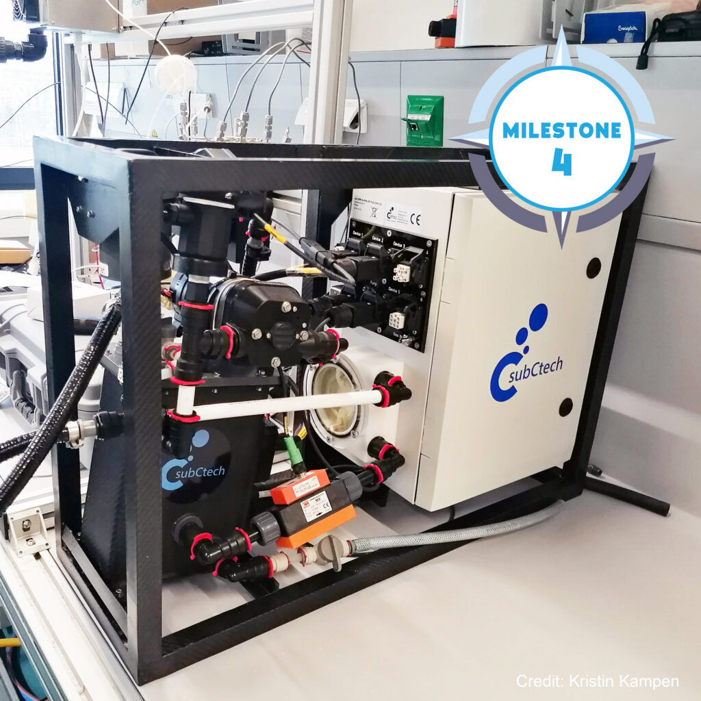 The OceanPack RACE sensor instrument in a lab from SubCtech. Pasted on the picture in the top right corner is a TRICUSO milestone badge displaying 'Milestone 4'.