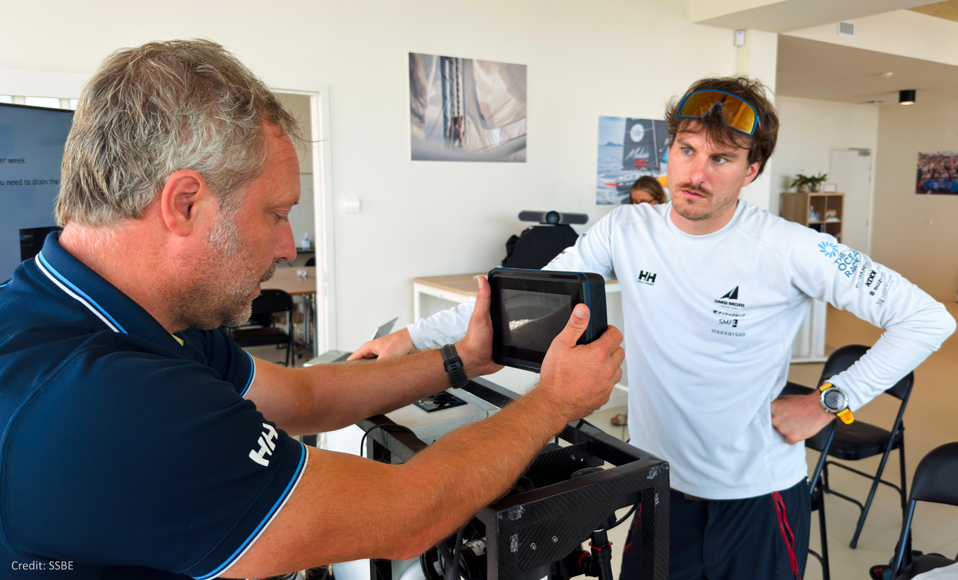 Two male sailors studying the OceanPack instrument attentively.
