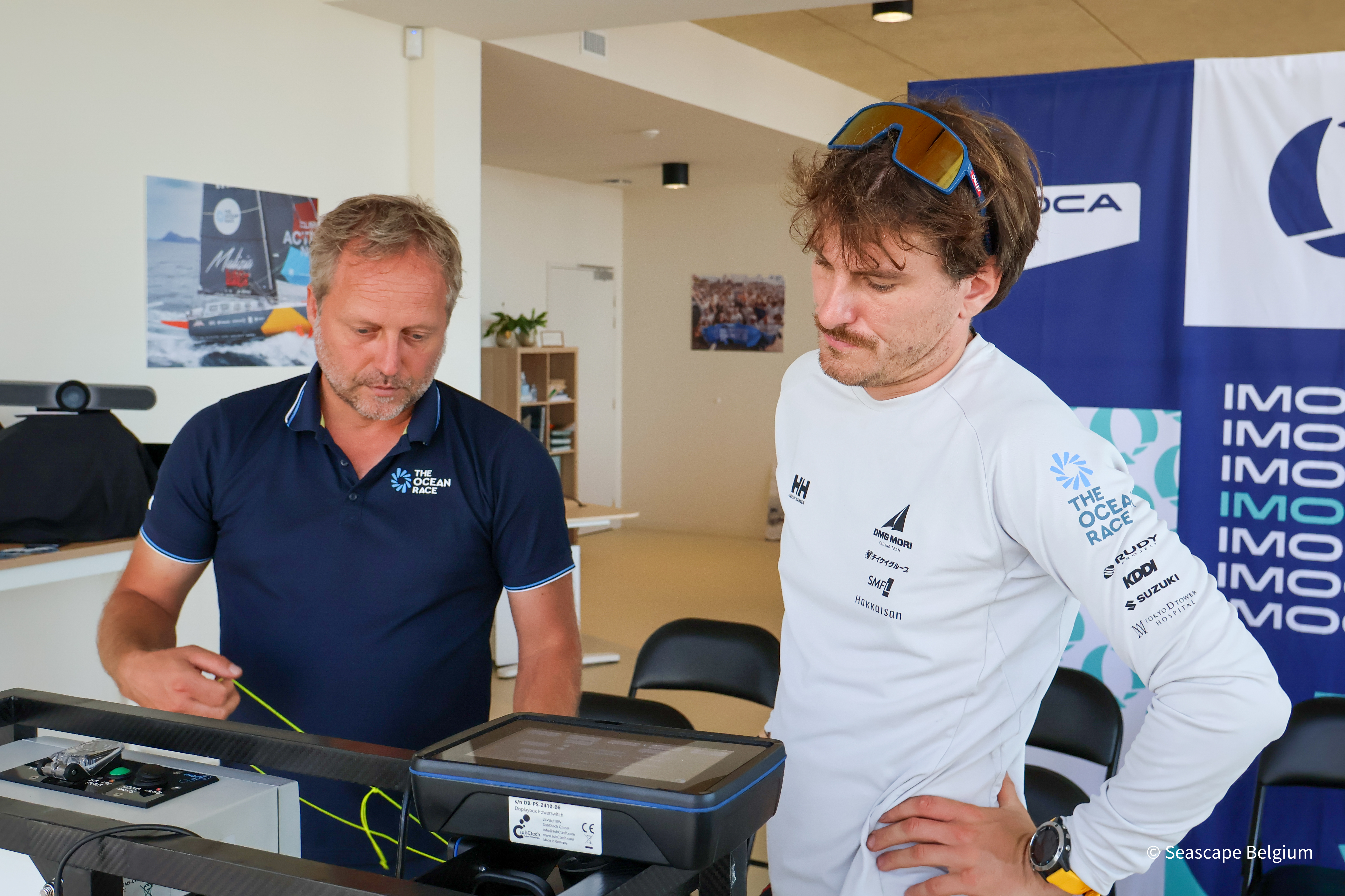 Two male sailers studying the OceanPack instrument attentively.